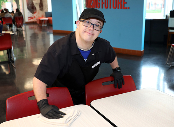 Man with Down Syndrome cleaning table in cafeteria 