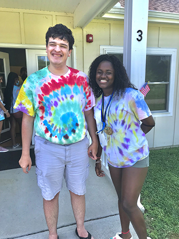 Two people in tie-dyed shirts standing in front of a cabin door at Camp Fairlee.