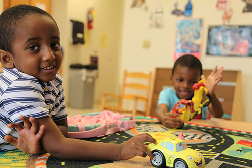 boys playing with cars at a table