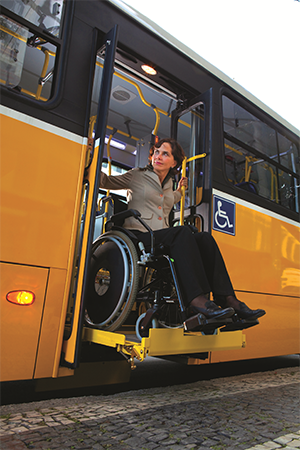 A woman in a wheelchair on a bus lift looking off to her right