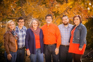 The Gaither family outside with fall foliage in the background
