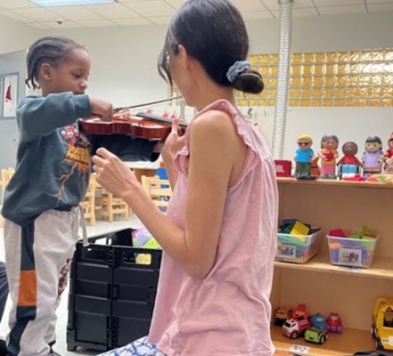 Ms. Saori teaching Azir to play violin