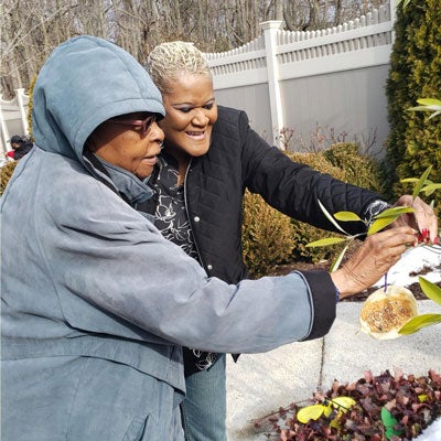 woman hangs handmade bird feeder in garden