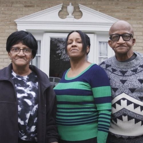 Linda, Gail, and William stand together in front of their home.