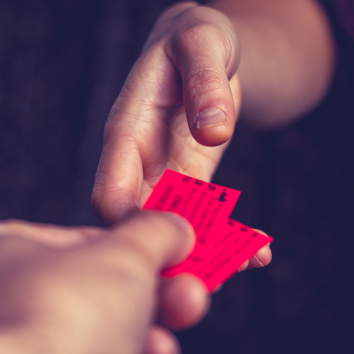 Person handing another person two red tickets