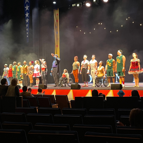 Circus performers lined up together across a stage for their standing ovation