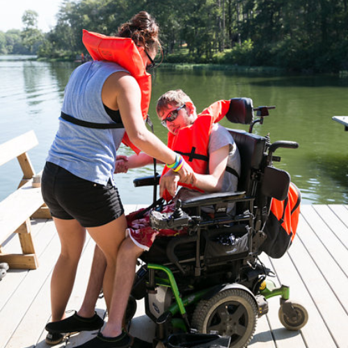 Boy in wheelchair wearing a life jacket on a dock