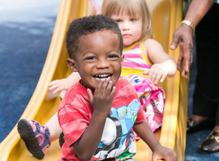 A boy and girl going down a yellow slide.