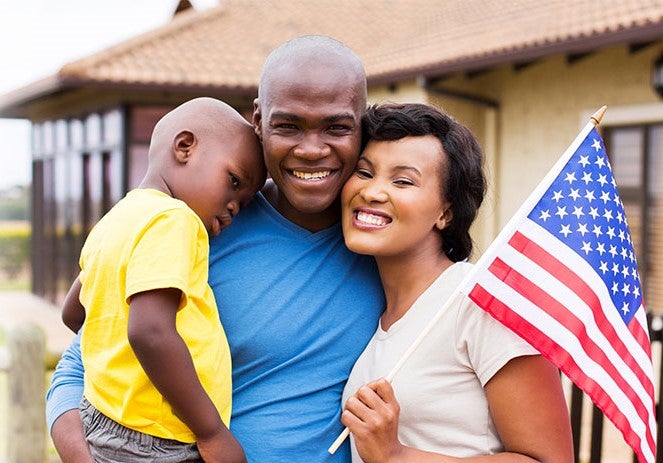 A mother, father, and young child pose together with the American flag