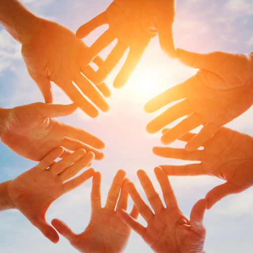 A group of people putting there hands together in a circle.