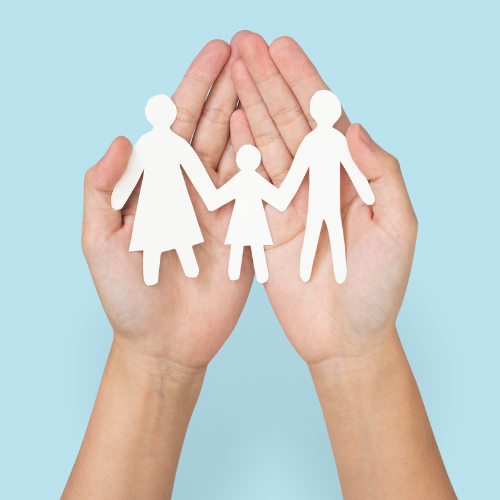 A person holding out a paper cutout of a family in the palms of their hands.