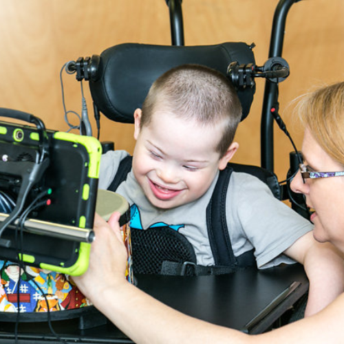 Boy with assistive technology and therapist