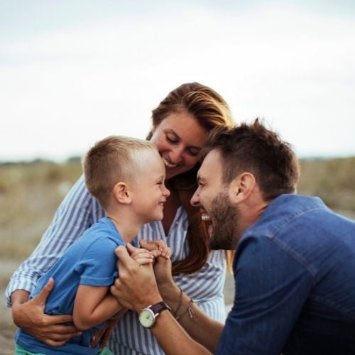 A family of three is huddled together smiling at each other