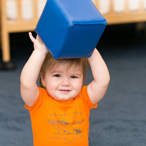 Baby holding a foam block above their head