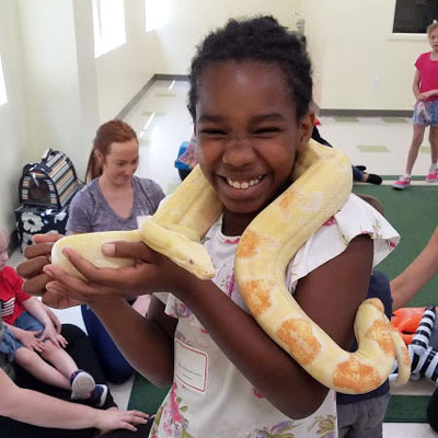 Child holds snake during respite program petting zoo