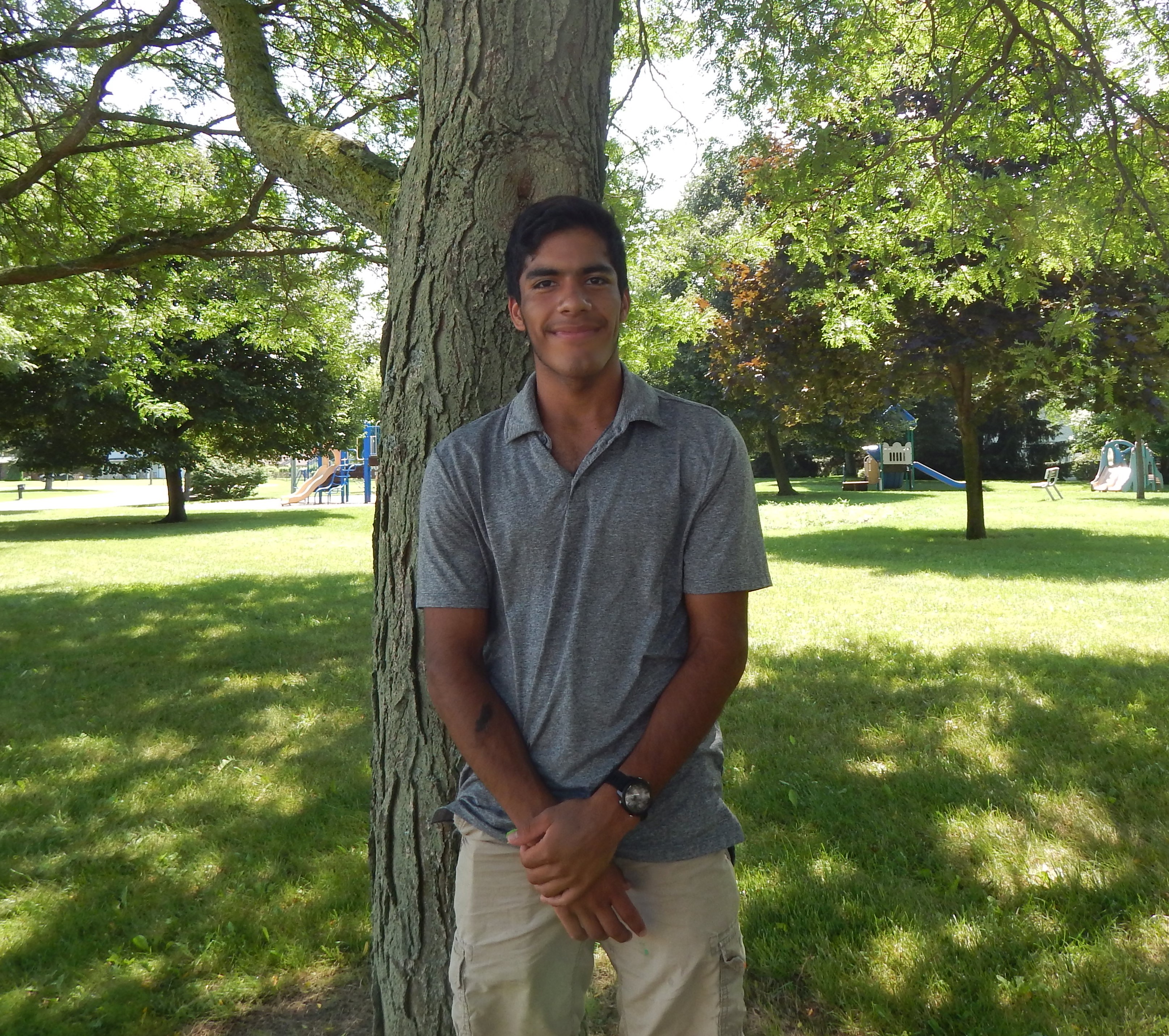 Photo of a young man, Gabe, posing by a tree