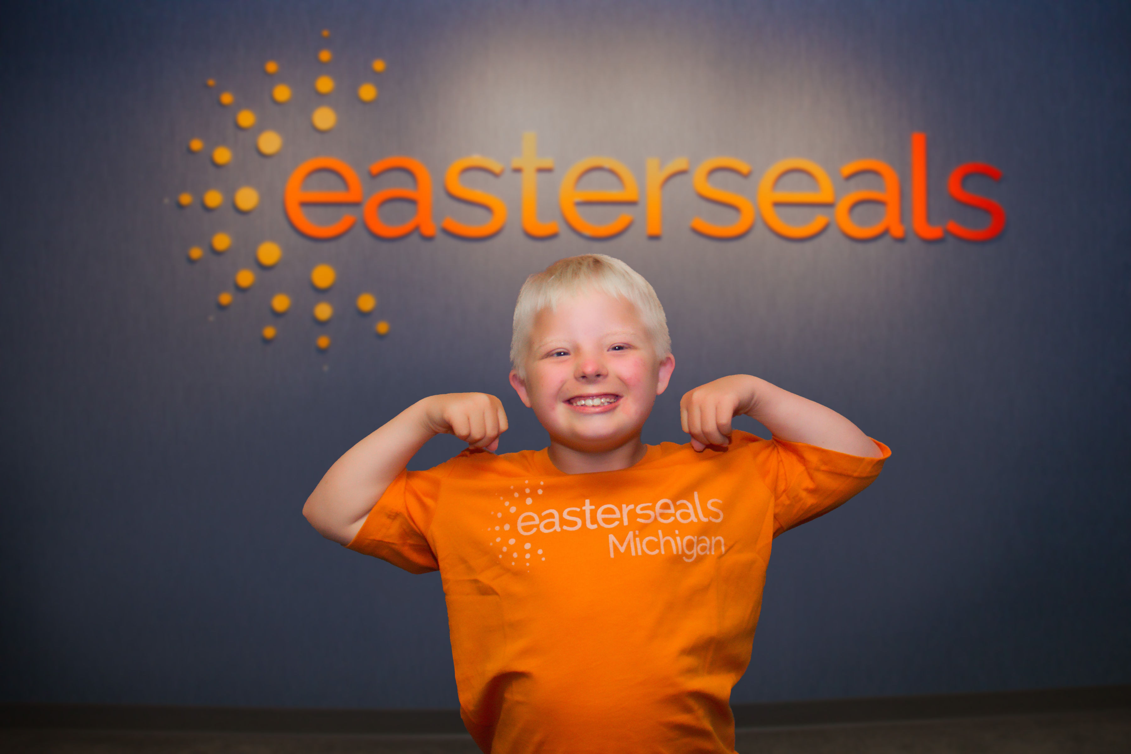 Brody with orange ESM shirt flexing muscles