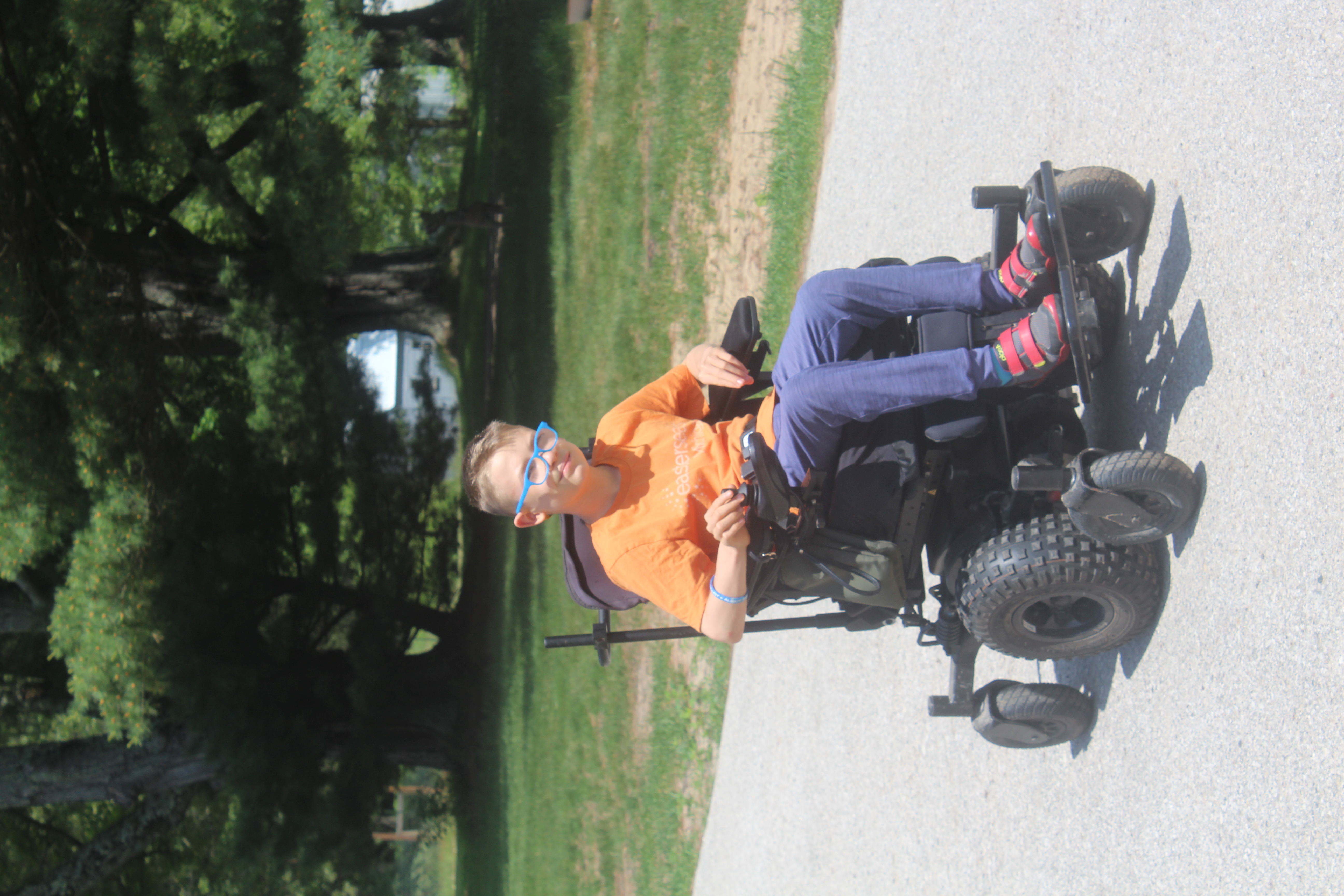 Evan in orange shirt, power chair in use