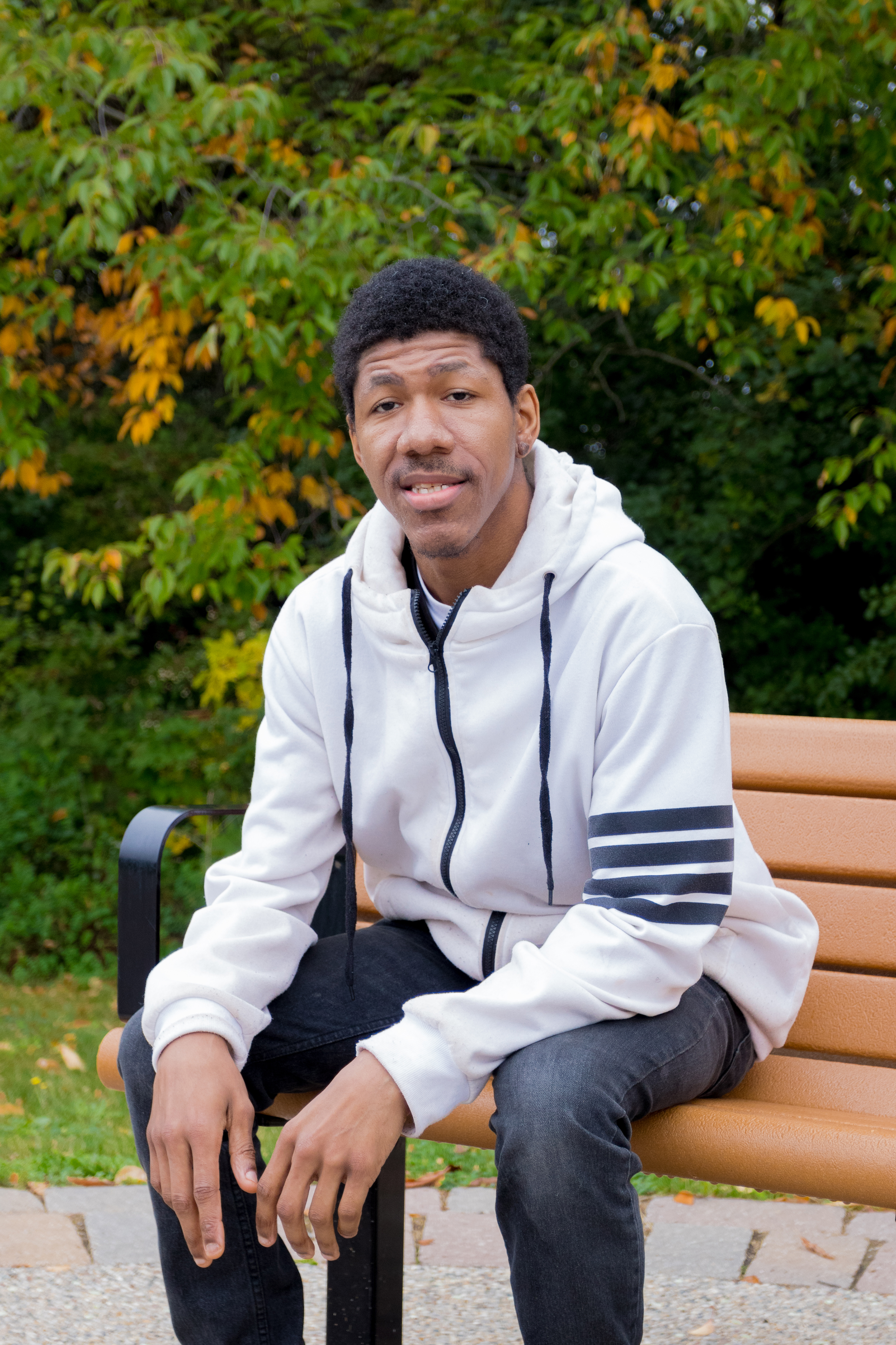 Justin sitting on a bench with a fall background