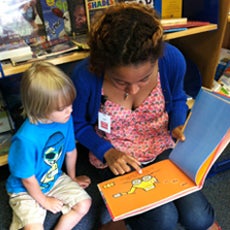 volunteer reading a book to a little boy