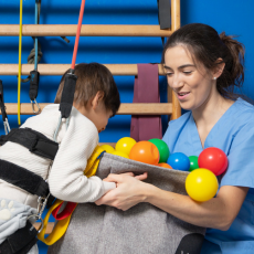 a nurse plays with a boy and has colorful plastic balls around