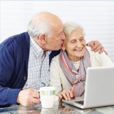 a older man and woman sitting at a computer