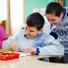 two young boys at a table playing a board game indoors