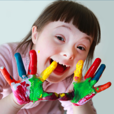 a photo of a girl with finger paint on her hands, holding them up to the camera