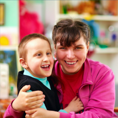 a young boy and a woman sit at a table and smile at the camera