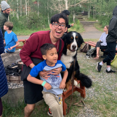camper and counselor smiling and posing near a large dog
