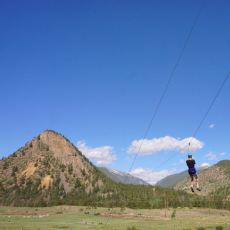 camper on zip line, mountains in the background