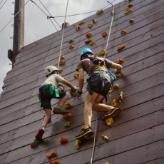 a camper and counselor climbing the climbing wall to zip line