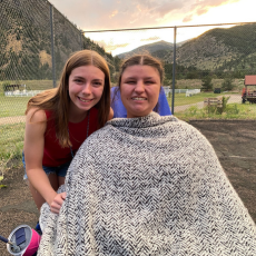 a camper and counselor smiling at the camera in front of a sunset