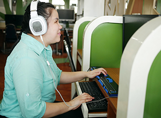 Person with a visual disability uses a screen reader while sitting down in front of a computer