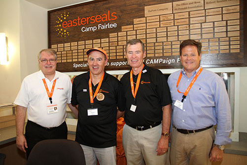 (l-r) Easterseals President/CEO, Ken Sklenar; Easterseals Board Members and CAMPaign Fairlee Co-chairs, David Doane and John Riley; and Easterseals Board Chair, Jeff Gosnear pose in front of the newly dedicated Donor Wall in the Activity Center at Easterseals Camp Fairlee.