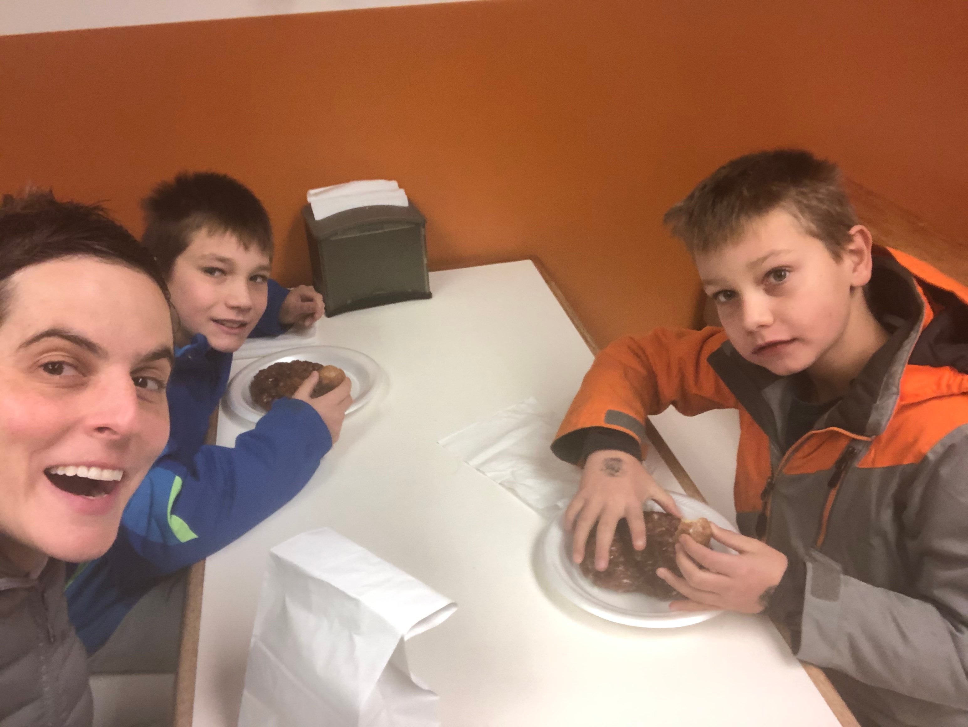 Mom and two sons eating donuts