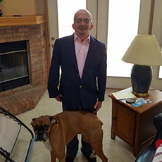 Dave stands in his living room with his dog.