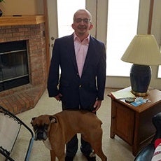 Dave stands in his living room with his dog.