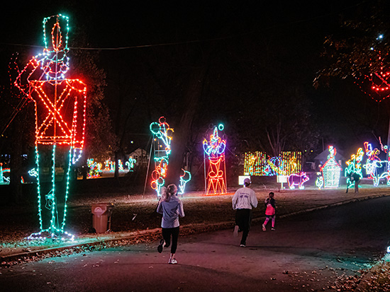 runners run past a large toy soldier light display with colorful displays in the background