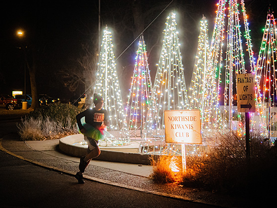 a runner runs past several lighted tree displays