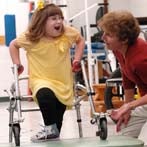 Ali steps up on a mat during a physical therapy session