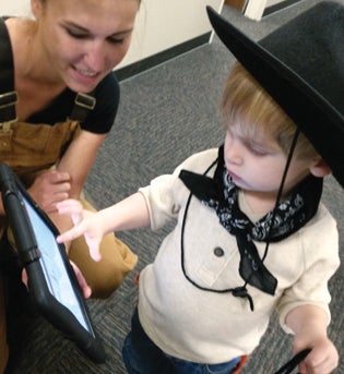 Thomas wearing a cowboy costume pointing at an iPad