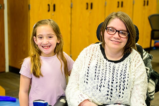 Eleanor Daywalt stands on the left side of Sage Hawkins as they both smile at the camera