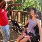 young girl in a wheel chair smiling with her friend at camp