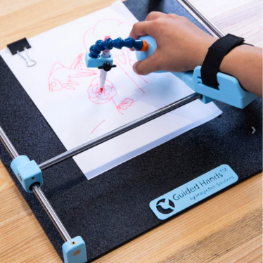 A hand uses the ImaginAble Solutions Guided Hands device to steadily draw a picture of a flower.