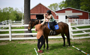 a leader high fives a client riding a horse while outside