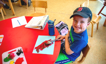 a young boy paints and smiles