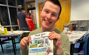 a boy smiles while holding up his vision board inside The Bridge Center