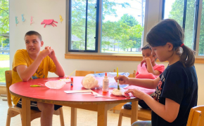 three children paint at The Bridge Center in a bright art room