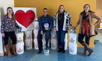 staff standing with paint cans and heart